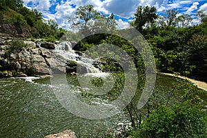 The waterfall on the river flows through and over the rocks cove