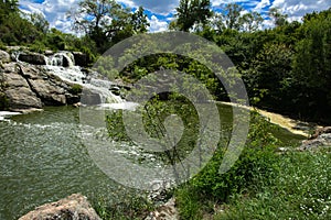 The waterfall on the river flows through and over the rocks cove