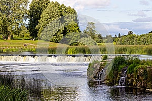 Waterfall in the river, trees and sky, summer