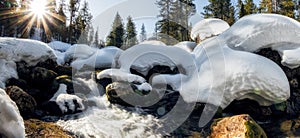 Waterfall on the river in winter among snowdrifts in a mountain forest