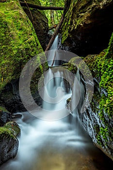 Waterfall through the rock chasm in mountain gully