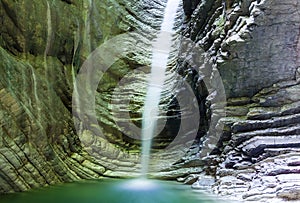 Waterfall in a rock with shiny water lit by sunlight water