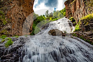Waterfall and rock with trees aunder sky