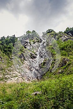 Waterfall between rocks flowing from mountain top.