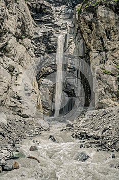 Waterfall among rocks and forests on the Alps