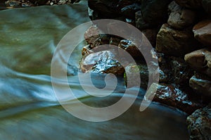 Waterfall and rocks with leaf in dark low key and long exposure