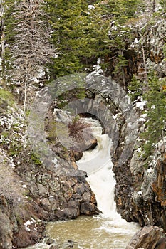 Waterfall in rocky ravine with melting snow