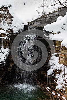Waterfall in the snowy winter forest in polish moutnains photo