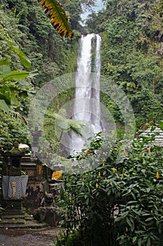 Waterfall with stone shrines and greenery in Bali countryside, Indonesia