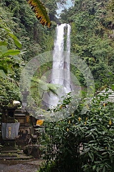 Waterfall with stone shrines and greenery in Bali countryside, Indonesia photo