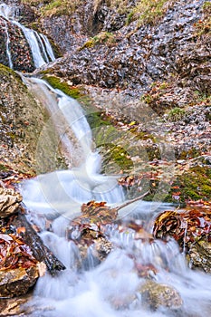 Waterfall on a stream in autumn forest.