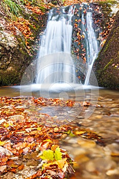 Vodopád na potoku v podzimním lese.