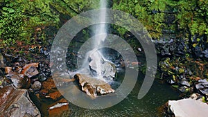 Waterfall stream crashing rocks aerial view. Force water falling mossy cliff