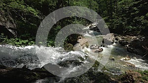 Waterfall stream falls down from hill to the river in the forest. Mountain river. Panorama. Wide andle shot. Top view