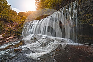Waterfall surrounded by moss, trees, and stones in Ystradfellte Neath UK
