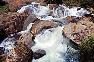 Waterfall with swift current between rocky stones photo