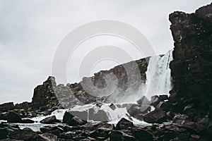 The waterfall in Thingvellir National Park, Iceland flowing from the river into the pool filled with rock