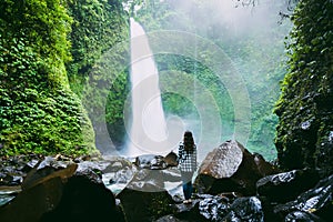 Waterfall in tropical jungle and alone woman. Waterfall in Bali