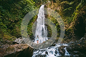 Waterfall in tropical jungle and alone woman. Waterfall in Bali