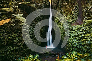 Waterfall in tropical jungle and alone woman in bikini. Leke Leke waterfall in Bali