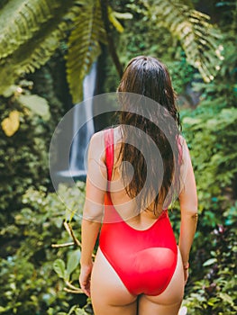 Waterfall in tropical jungle and alone woman in bikini. Leke Leke waterfall in Bali