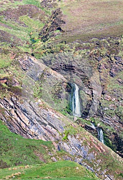 A waterfall tumbles through a narrow rocky gully in Scotland