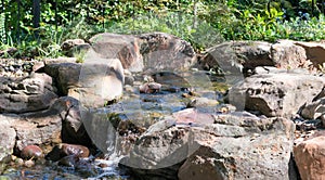 Waterfall tumbling slowly against rocks with dense green foliage