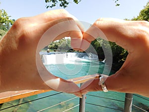 Waterfall on the background of a heart made by hands