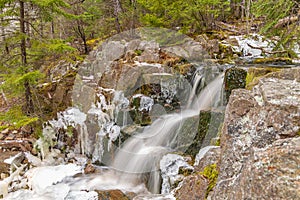 Waterfall in winter forest.l Hiking Trail. Rocks Ice and Moss