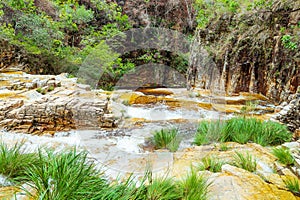 Waterfalls with golden tones, sedimentary rocks and the green vegetation