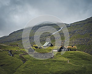 Waterfalls in the village of Saksun on the Faroe islands. No people around, traditional stone houses.