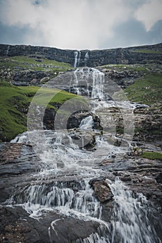 Waterfalls in the village of Saksun on the Faroe islands. No people around, traditional stone houses.