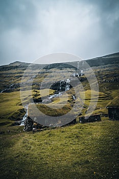 Waterfalls in the village of Saksun on the Faroe islands. No people around, traditional stone houses.