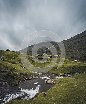 Waterfalls in the village of Saksun on the Faroe islands. No people around, traditional stone houses.