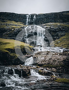 Waterfalls in the village of Saksun on the Faroe islands. No people around, traditional stone houses.