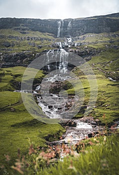 Waterfalls in the village of Saksun on the Faroe islands. No people around, traditional stone houses.