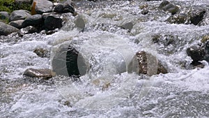 Waterflow of mountain river over stones in slow motion, close up