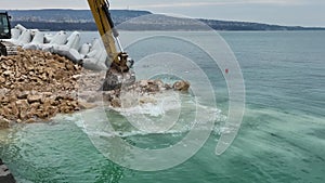 Waterfront construction site with excavator. Excavator working on a breakwater construction