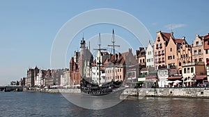 Waterfront with historical terraced houses, stylized old ship sailing on river