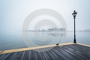 The Waterfront Promenade and fog over the harbor, in Fells Point, Baltimore, Maryland