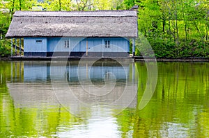 Waterfront wood house with thatched roof. Painted in blue
