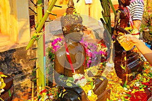 Watering Buddha statues with scented water and flower petals during Lao New Year - Pii Mai Lao - Song Kran - Water Festival in Apr