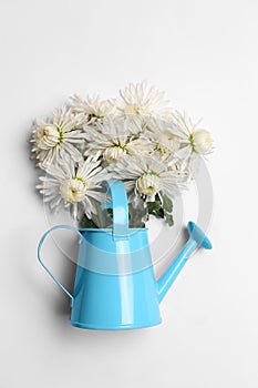 Watering can with beautiful flowers on white background, top view