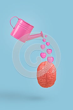 Watering can pouring pastel pink hearts. Creative minimal idea made of human brain with pink hearts and watering can