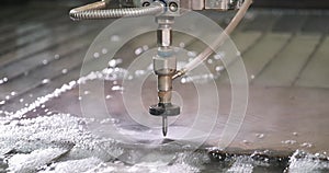 Waterjet high pressure CNC machine is cutting out a holes on a metal sheet.