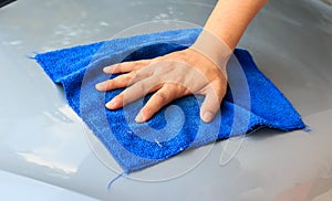 Waterless car wash. Men`s hand with blue cloth cleaning car