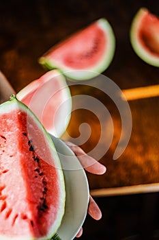 Slice of watermelon on white plate on hands photo