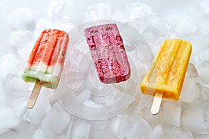 Watermelon, berry, peach, homemade ice lolly on ice cubes. Sweet cold dessert. Flat lay