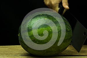 Watermelon big drop on wood, on a black background