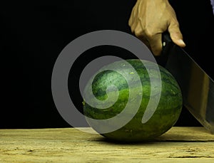 Watermelon big drop on wood, on a black background